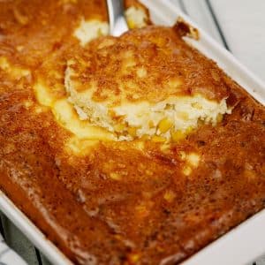 silver spoon in corn pudding in white baking dish