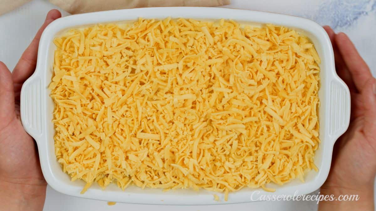 hands holding casserole dish with cheese on top