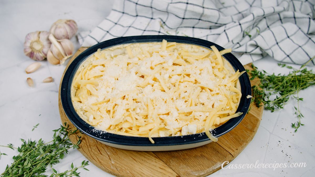 shredded cheese on top of baking dish of au gratin potatoes