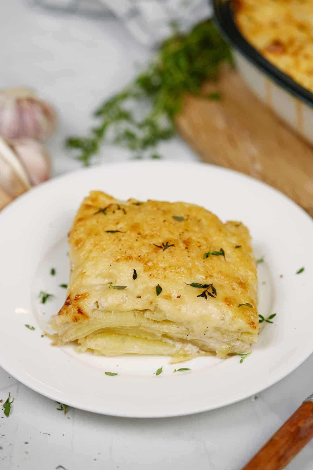 square of potato casserole with herbs on top sittingo n white plate