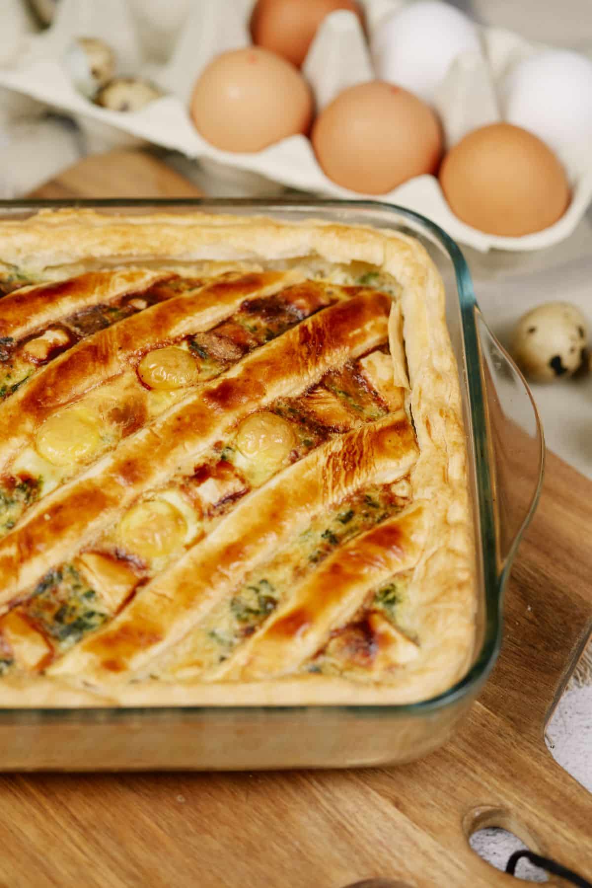 puff pastry on egg casserole in glass baking dish on wood cutting board