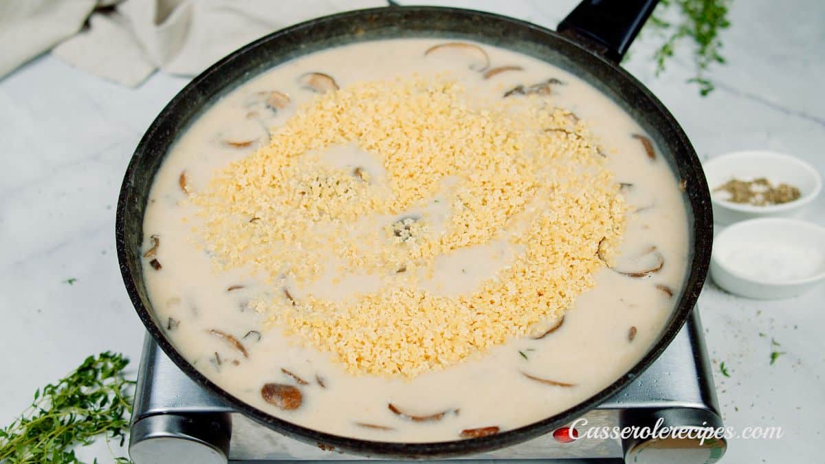 pasta being added to cream sauce in skillet
