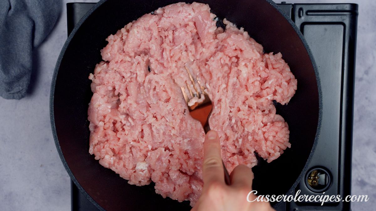 raw ground meat in black skillet on hot plate 