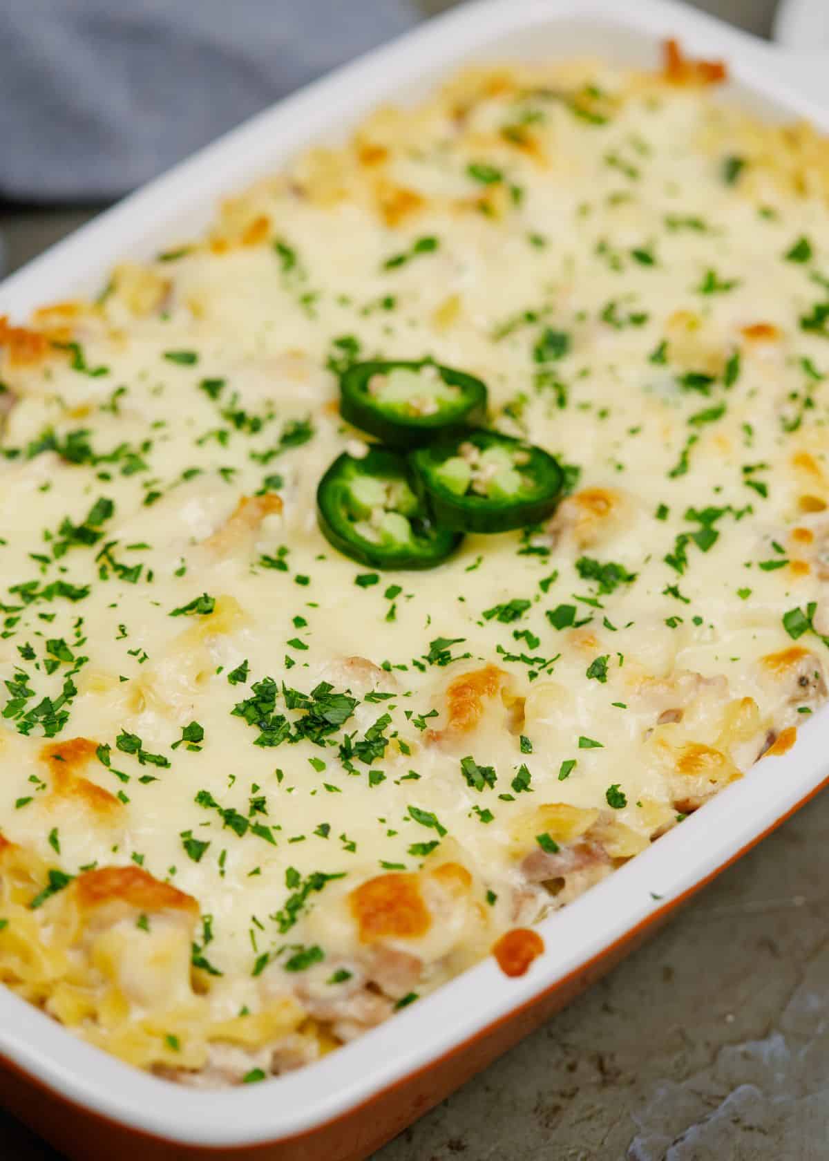 rectangle baking dish of jalapeno popper chicken casserole topped with sliced jalapenos