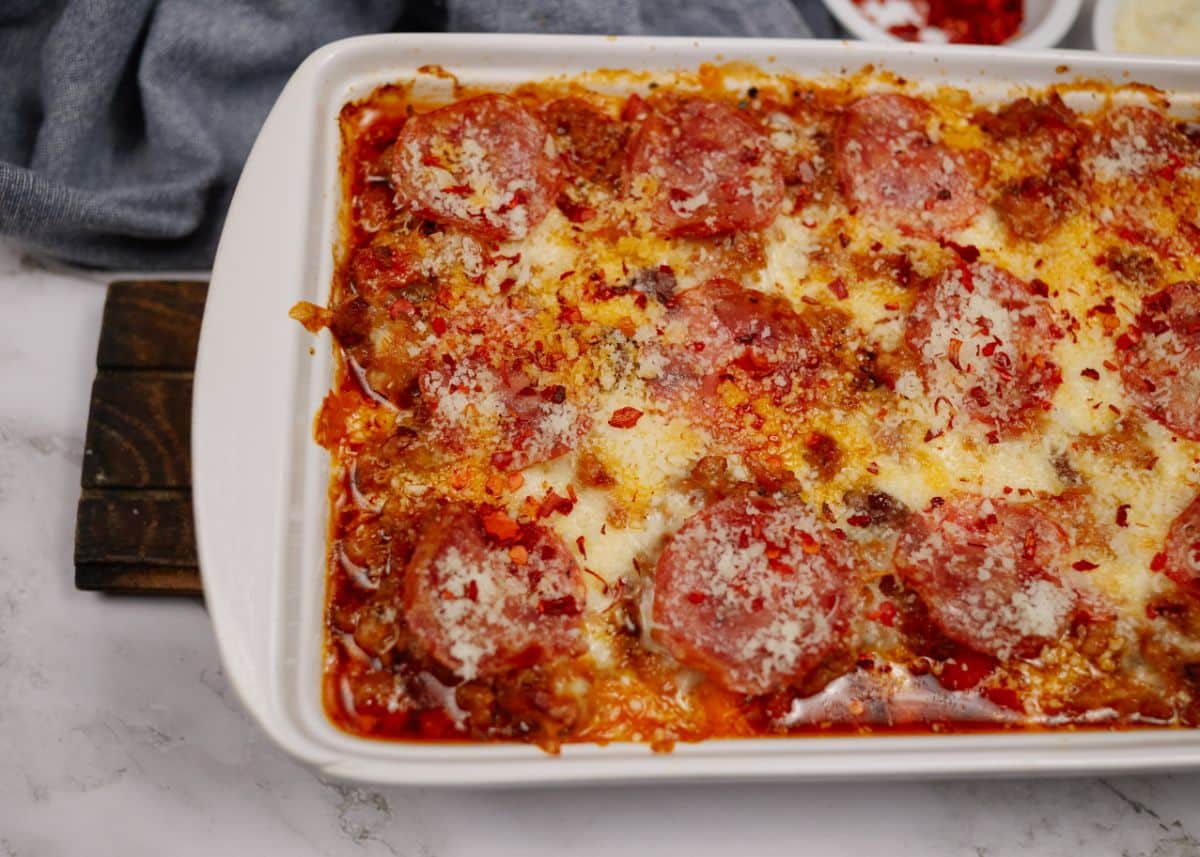 keto pizza casserole in white baking dish topped with salami and cheese