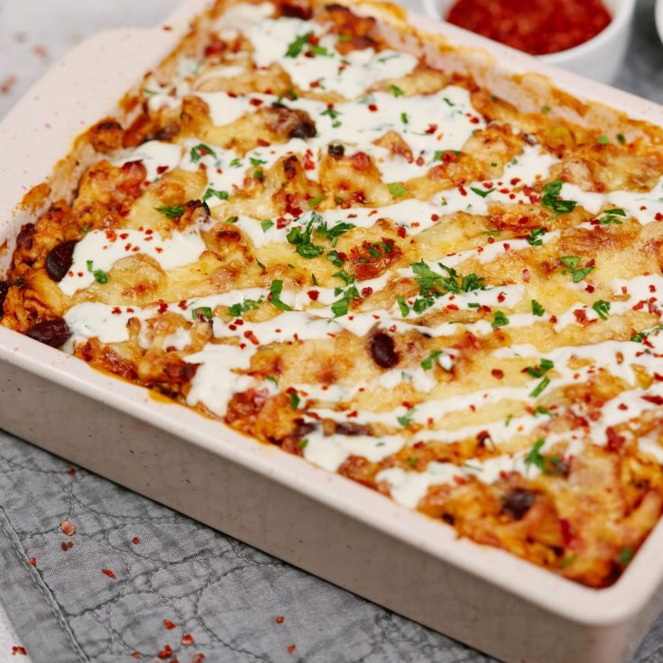 square white baking dish of casserole topped with sour cream and herbs