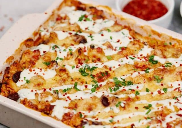 square white baking dish of casserole topped with sour cream and herbs