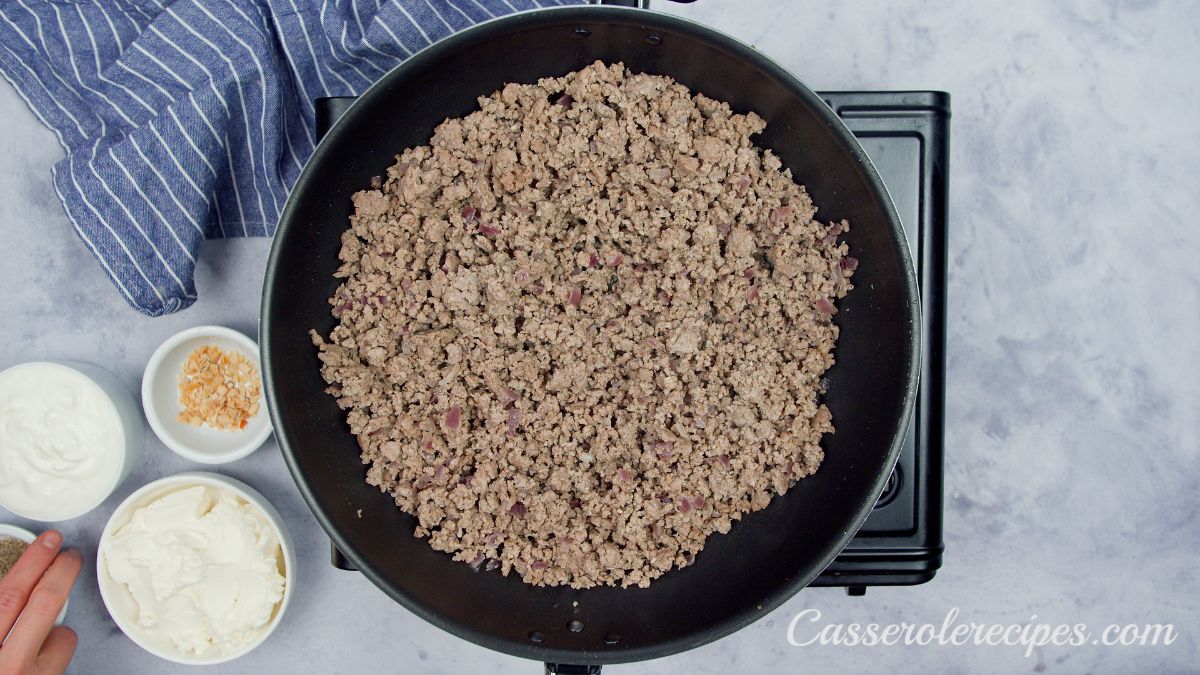 black skillet of cooked ground beef on hot plate