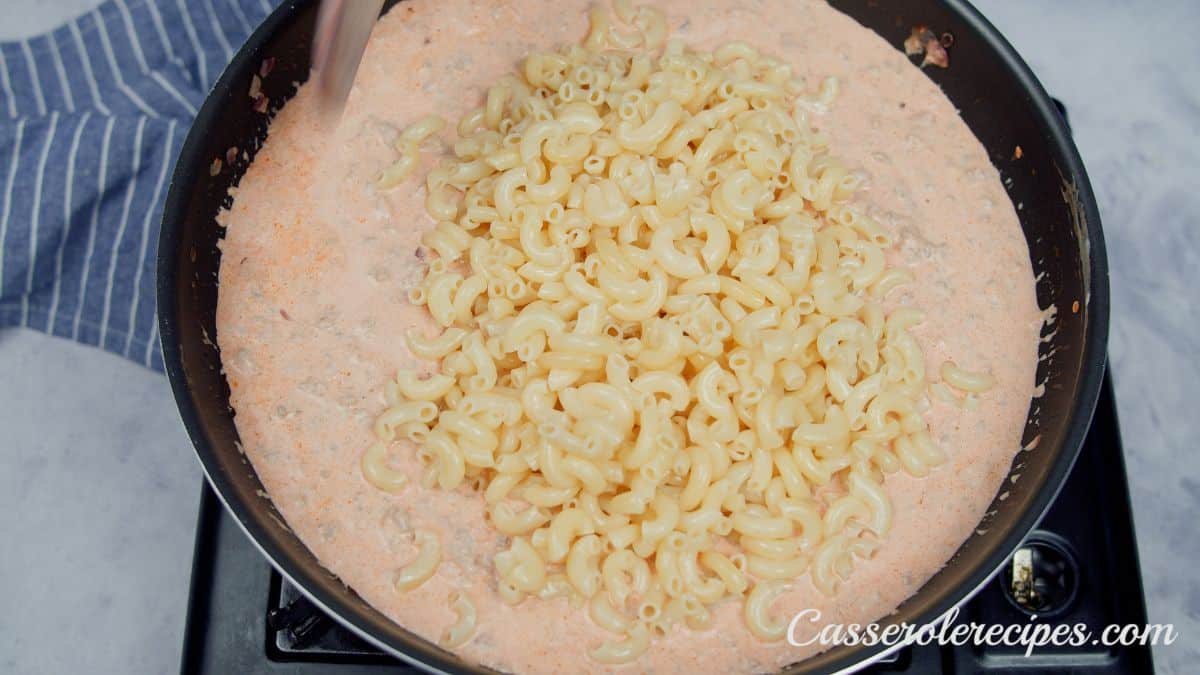 cooked pasta being stirred into meat and cheese sauce
