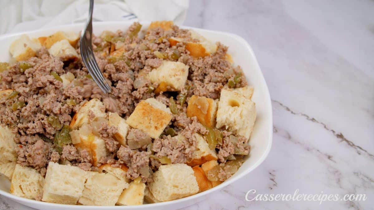sausage being added to casserole with bred