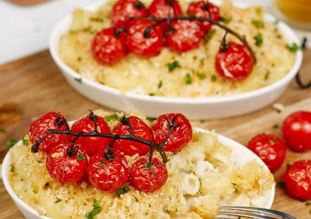 two white ramekins of shrimp casserole topped by red tomatoes on cutting board