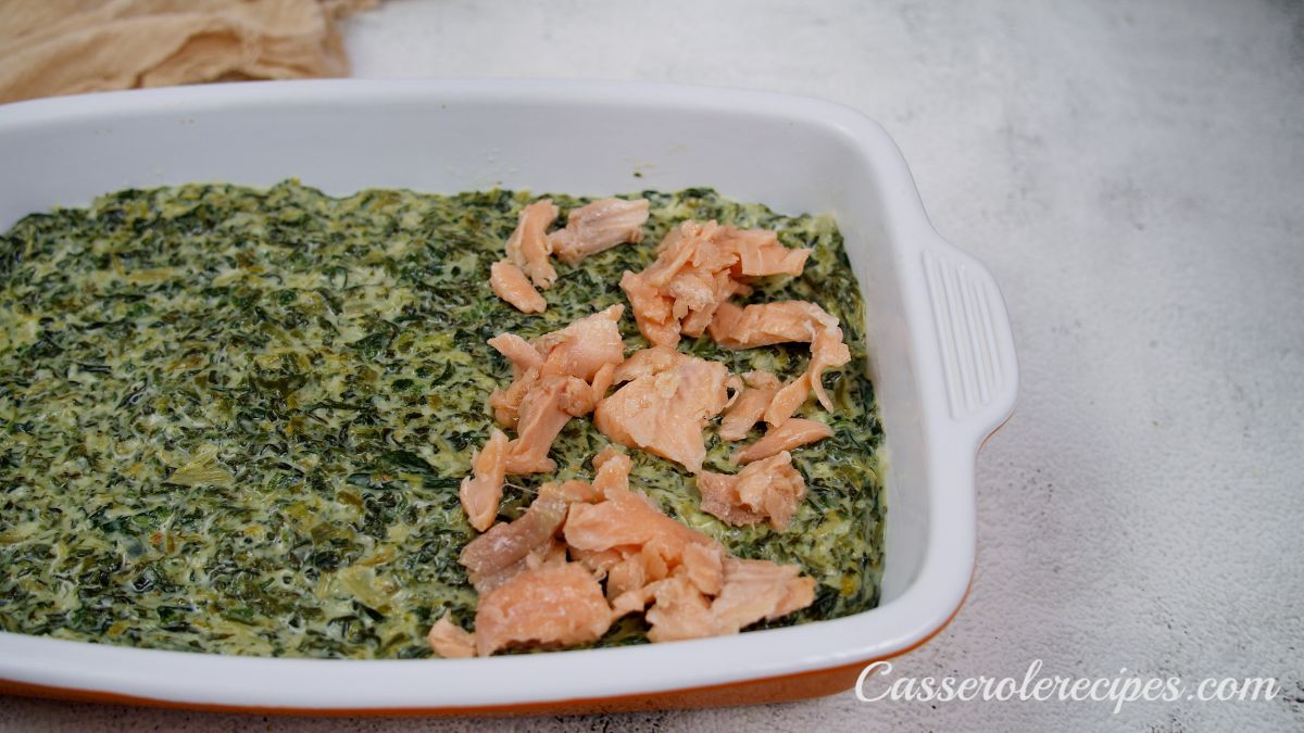salmon being places on spinach in casserole dish