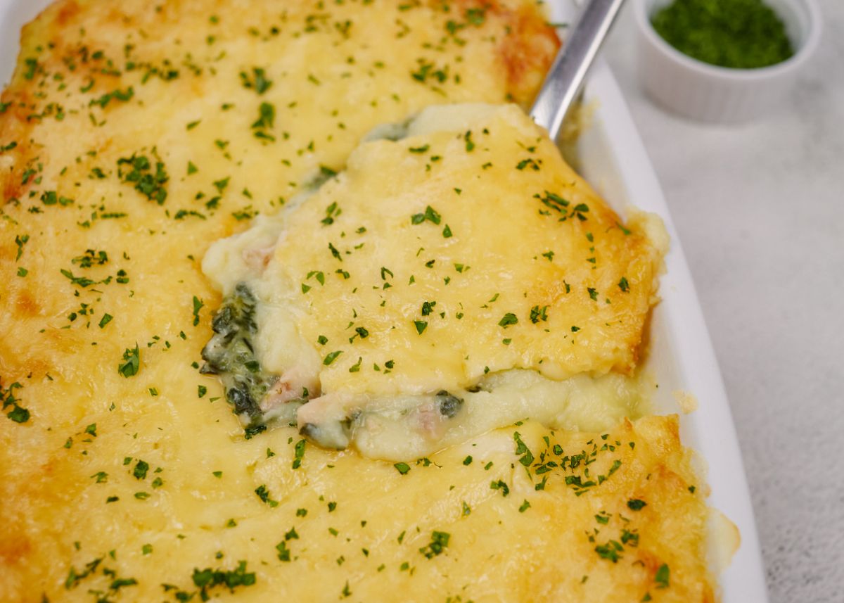 white baking dish of salmon and spinach casserole with spoon in side of dish