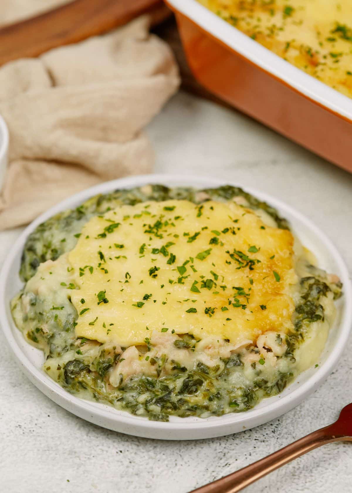 round white plate of salmon and spinach casserole on white table