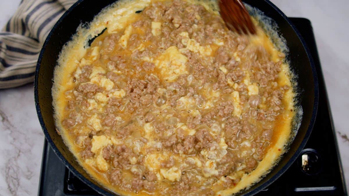 beaten eggs in skillet with cooked ground beef