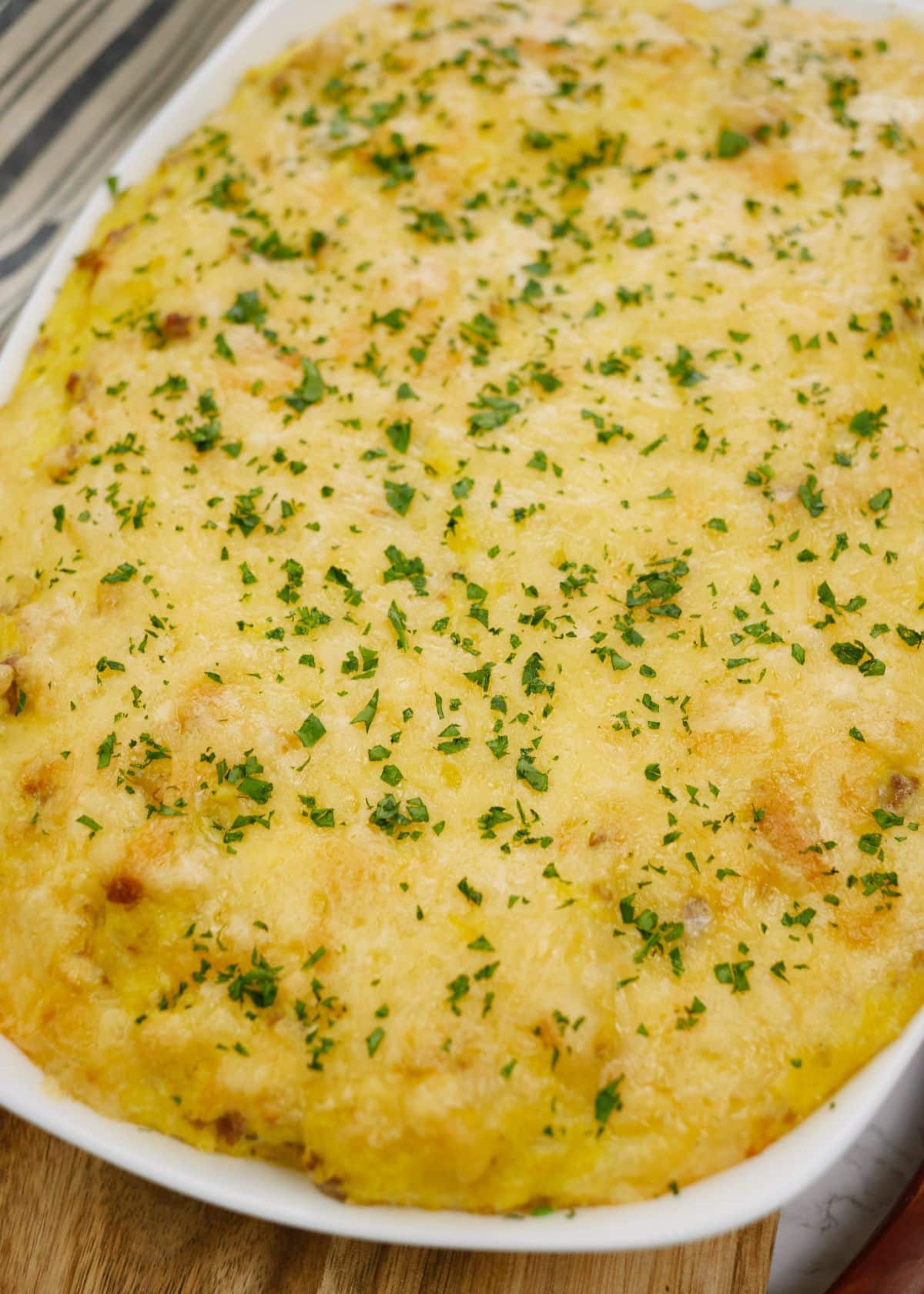 Southern grits casserole in white baking dish on wooden board