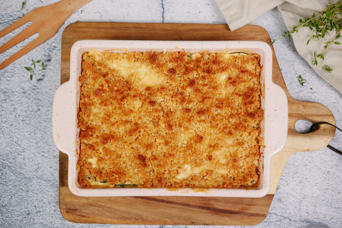 summer squash casserole in square pink baking dish on top of cutting board