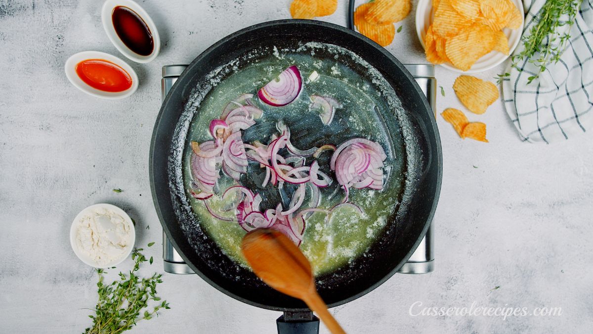 wooden spoon stirring red onions in butter in skillet