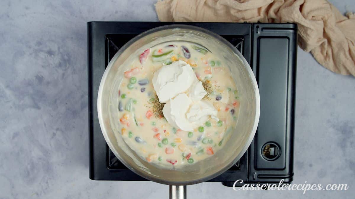 cream cheese in the center of skillet with cream and vegetables