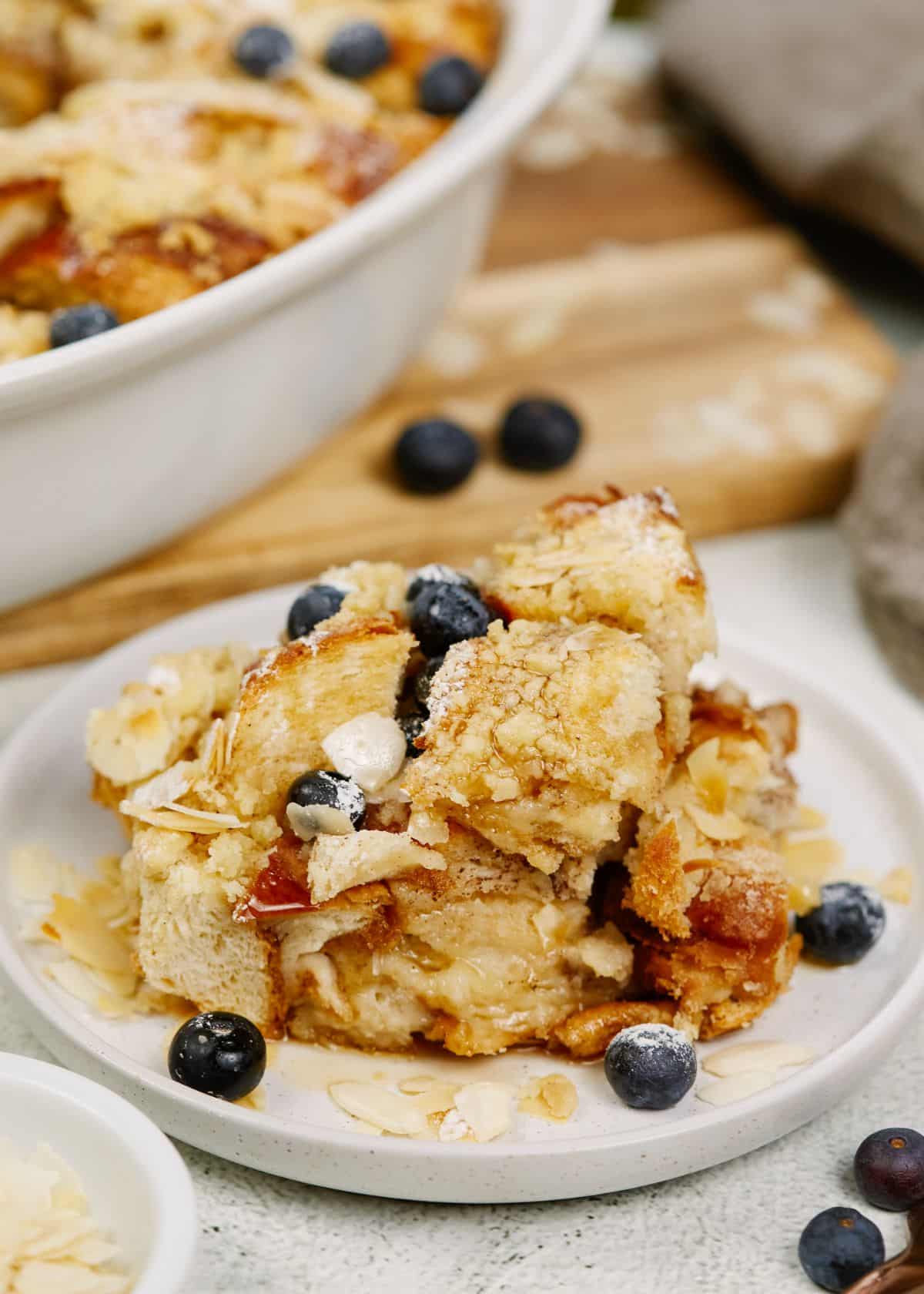 white plate of french toast casserole topped with blueberries and syrup