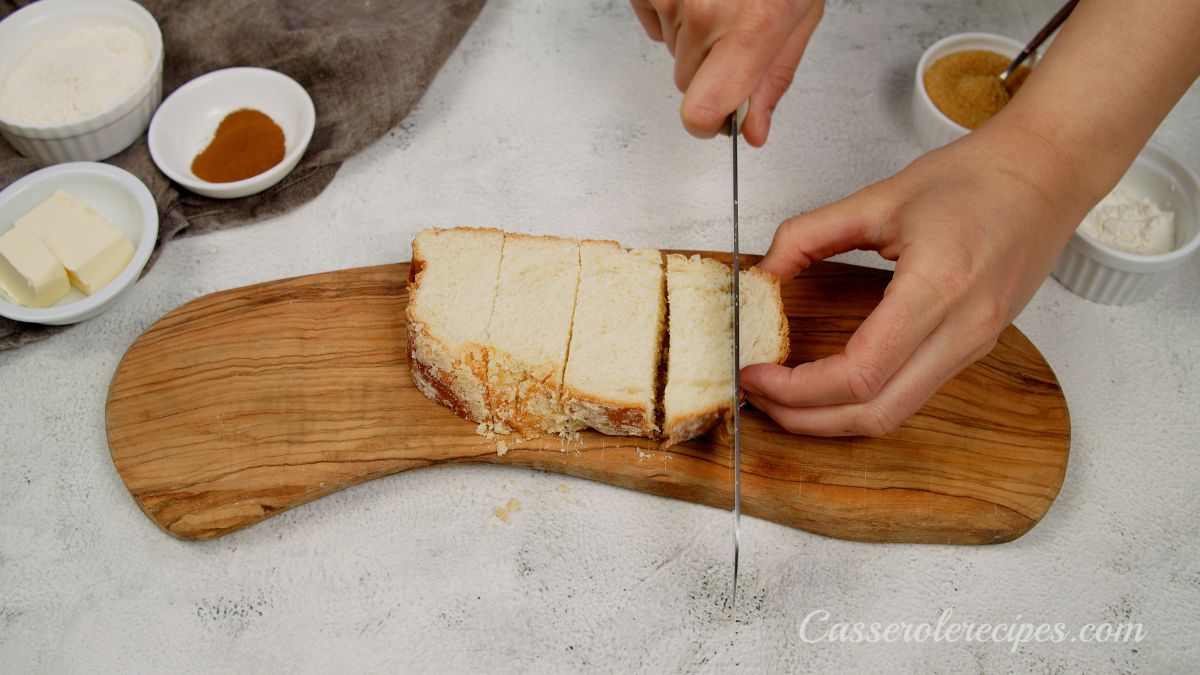 hand slicing brioche on wood cutting board