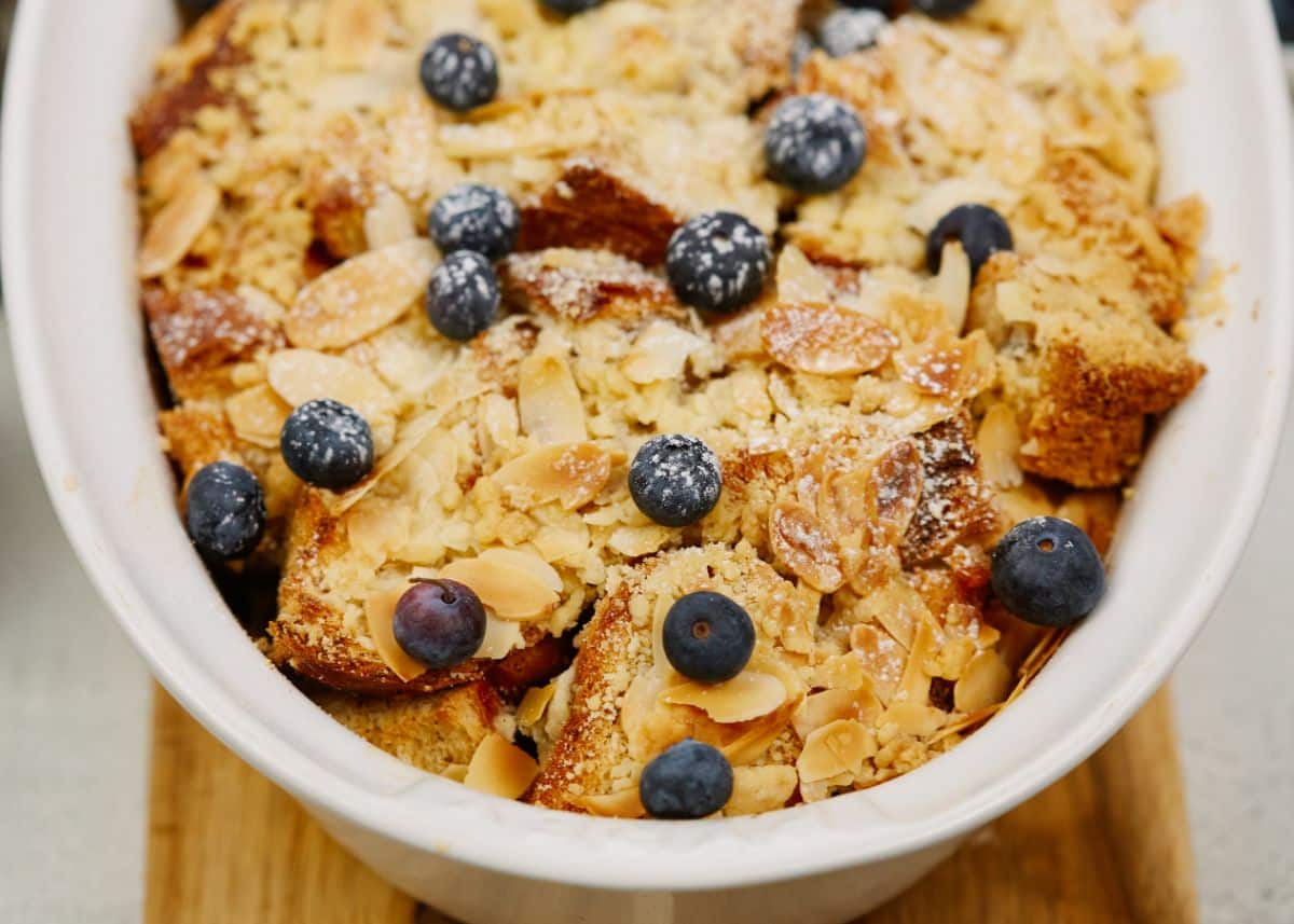 oval white baking dish of vegan french toast casserole with almonds and blueberries