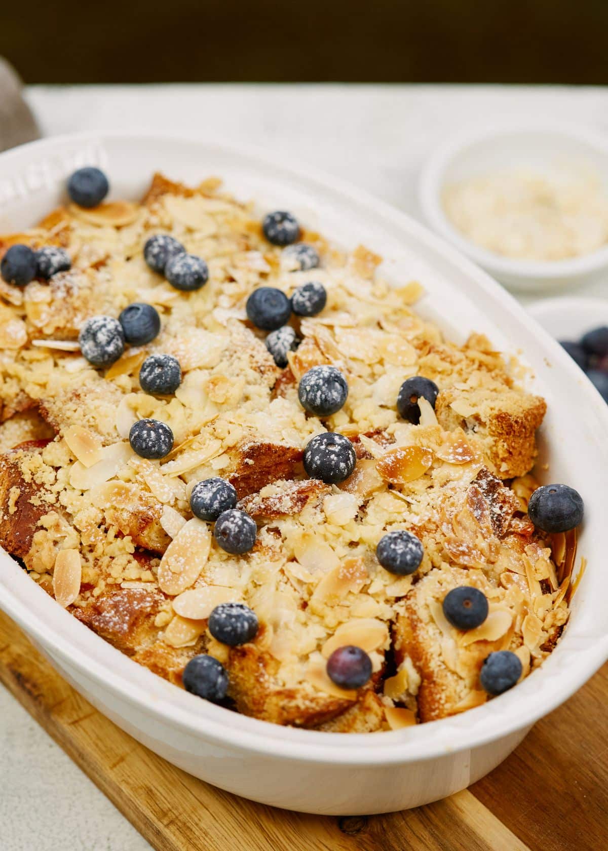 oval baking dish of vegan french toast casserole sitting on a wood cutting board