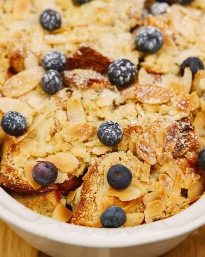 oval white baking dish of vegan french toast casserole with almonds and blueberries