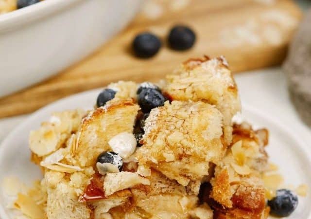white plate of french toast casserole topped with fresh blueberries