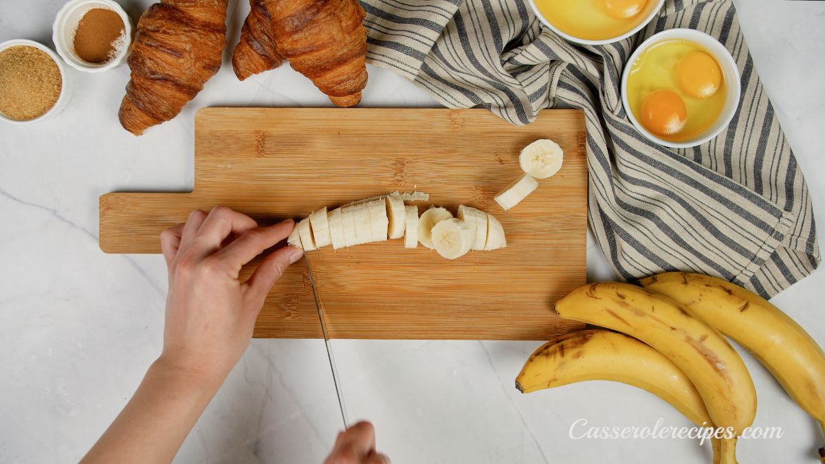 hand slicing bananas on wood cutting board