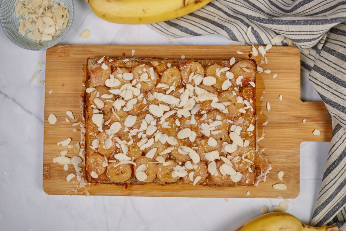 bananas foster breakfast casserole on cutting board by striped napkin with bananas in background