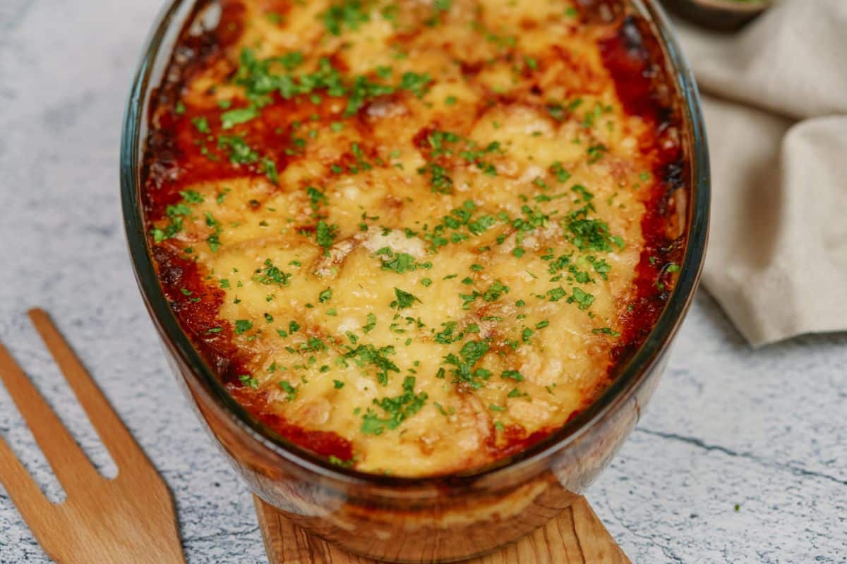 ground beef and potato casserole with tomato sauce and cheese in glass dish