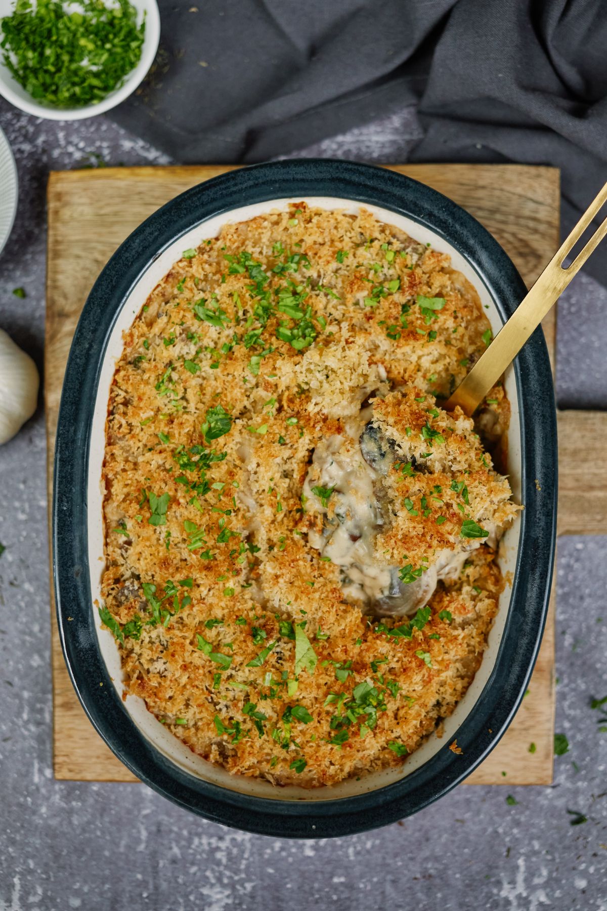 black baking dish of parmesan mushroom casserole with gold spoon in side