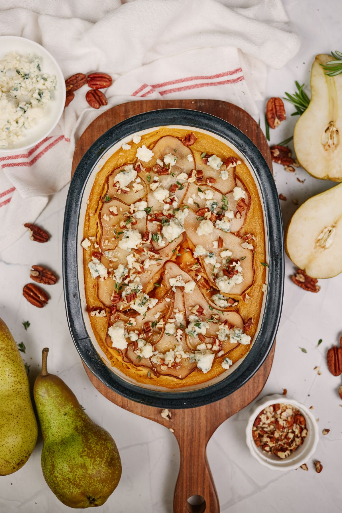 oval baking dish of sweet potato casserole with pears sitting on top of cutting board