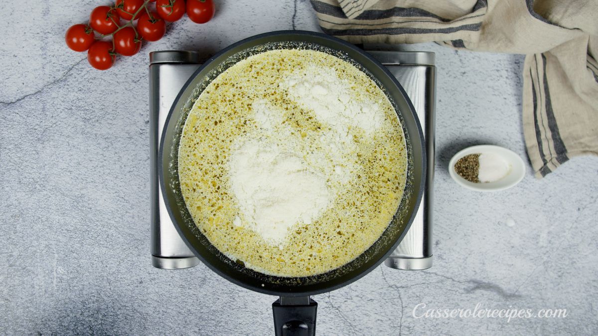 cheese being added to pesto sauce in skillet on hot plate
