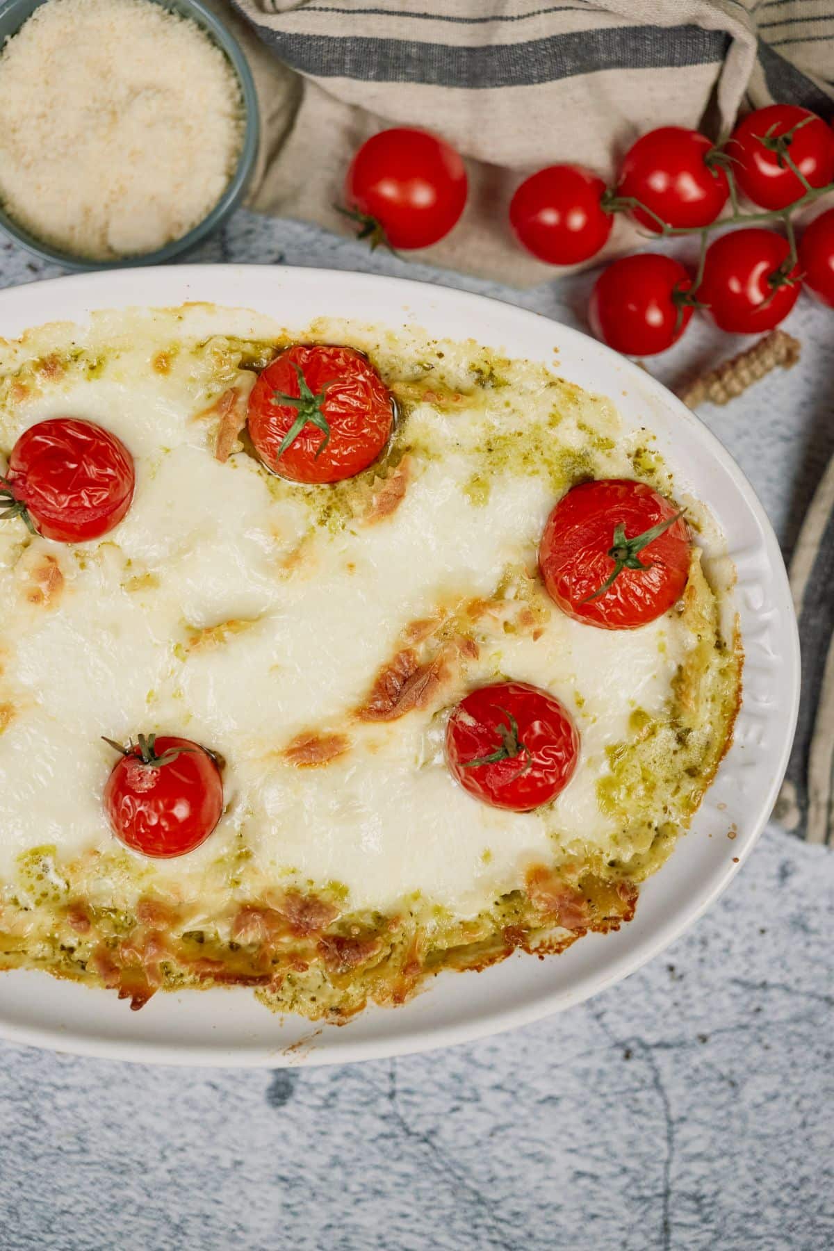 white baking dish of pesto pasta casserole topped with tomatoes