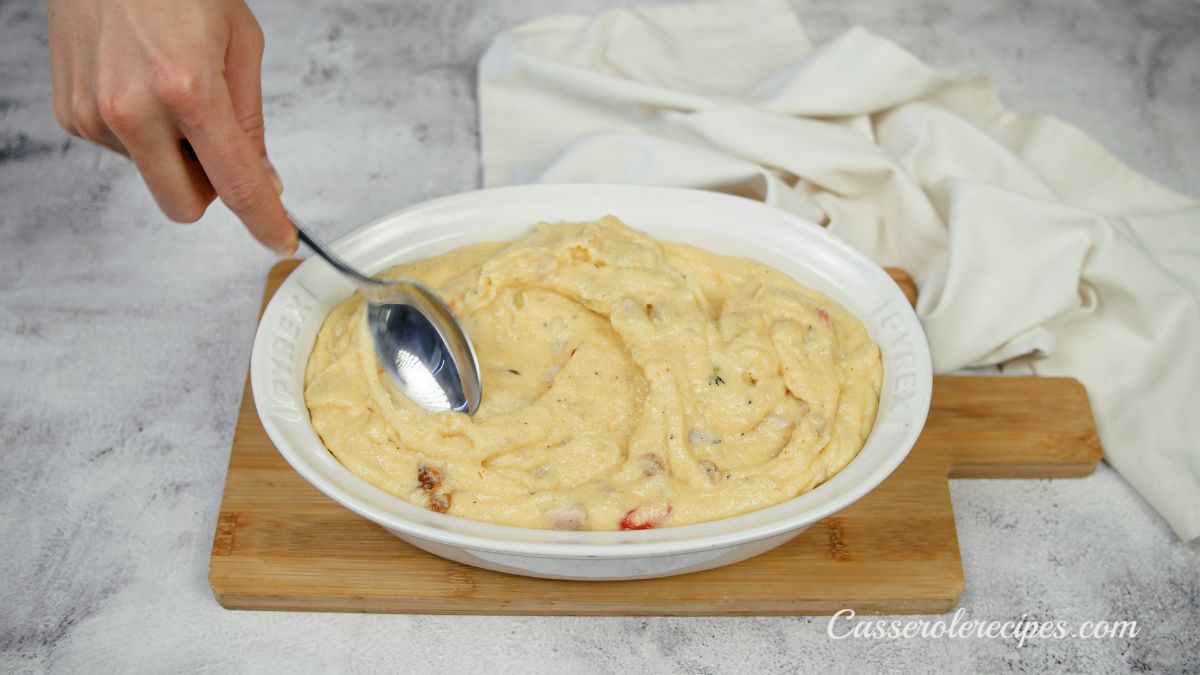 spoon spreading polenta in baking dish