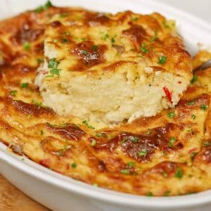 spoon lifting a portion of polenta breakfast casserole in baking dish