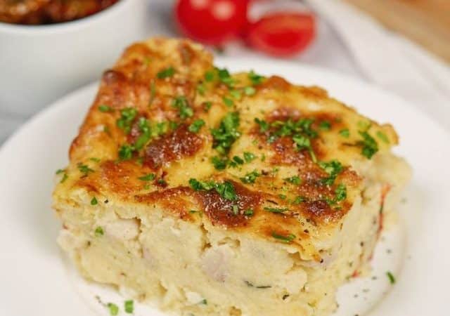 slice of polenta breakfast casserole on white plate by cherry tomatoes