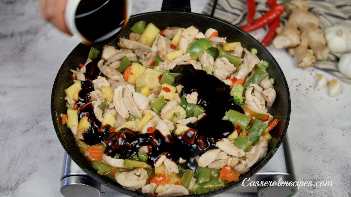 black skillet of chicken with sauce being poured into it