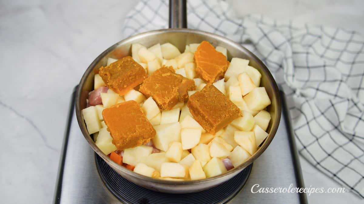 curry roux blocks on top of potatoes in large deep skillet