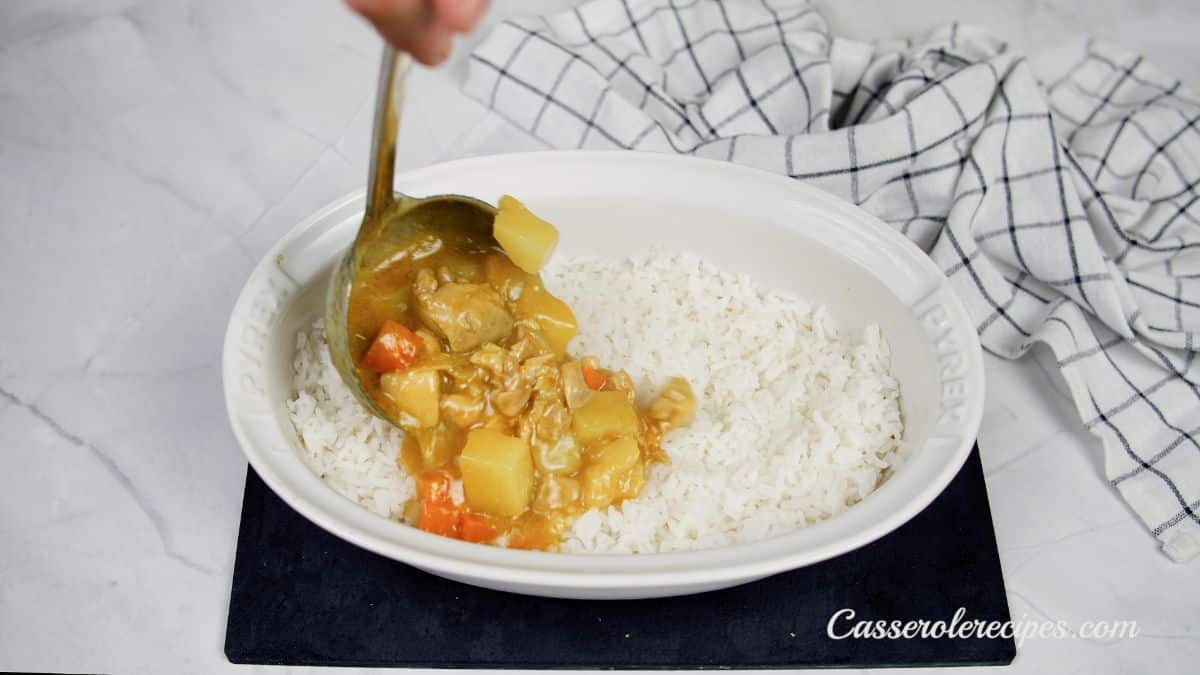 curry being poured over rice in baking dish