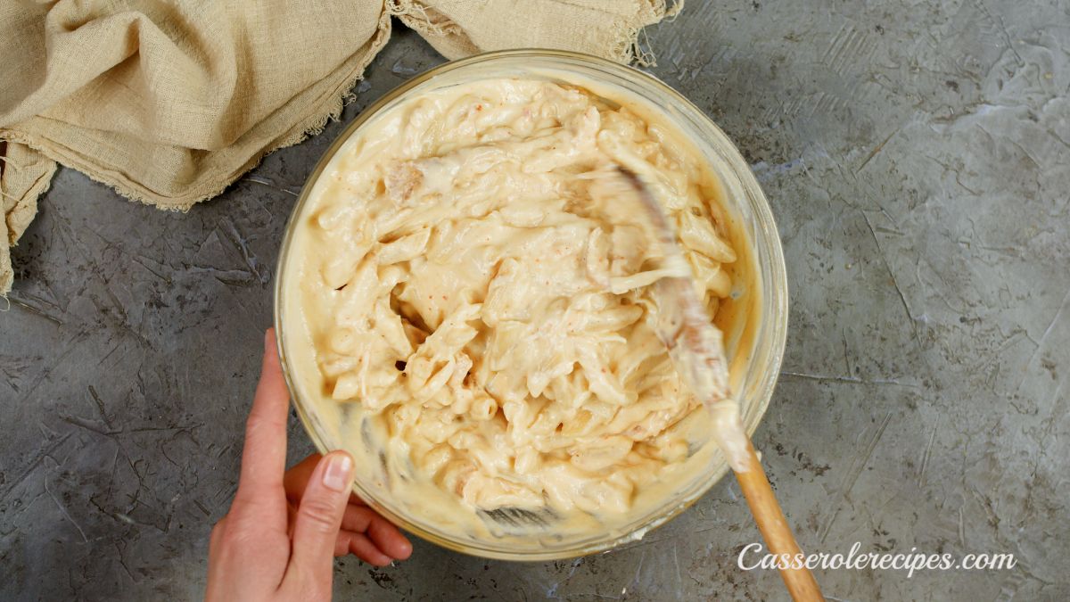 glass bowl of chicken and pasta being mixed