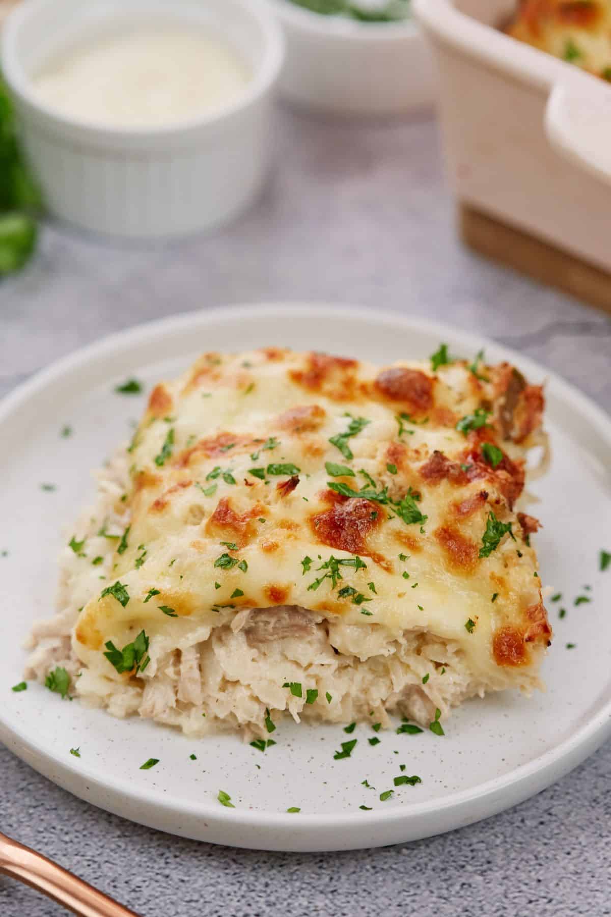 plate holding a serving of chicken thighs and cauliflower casserole topped with parsley