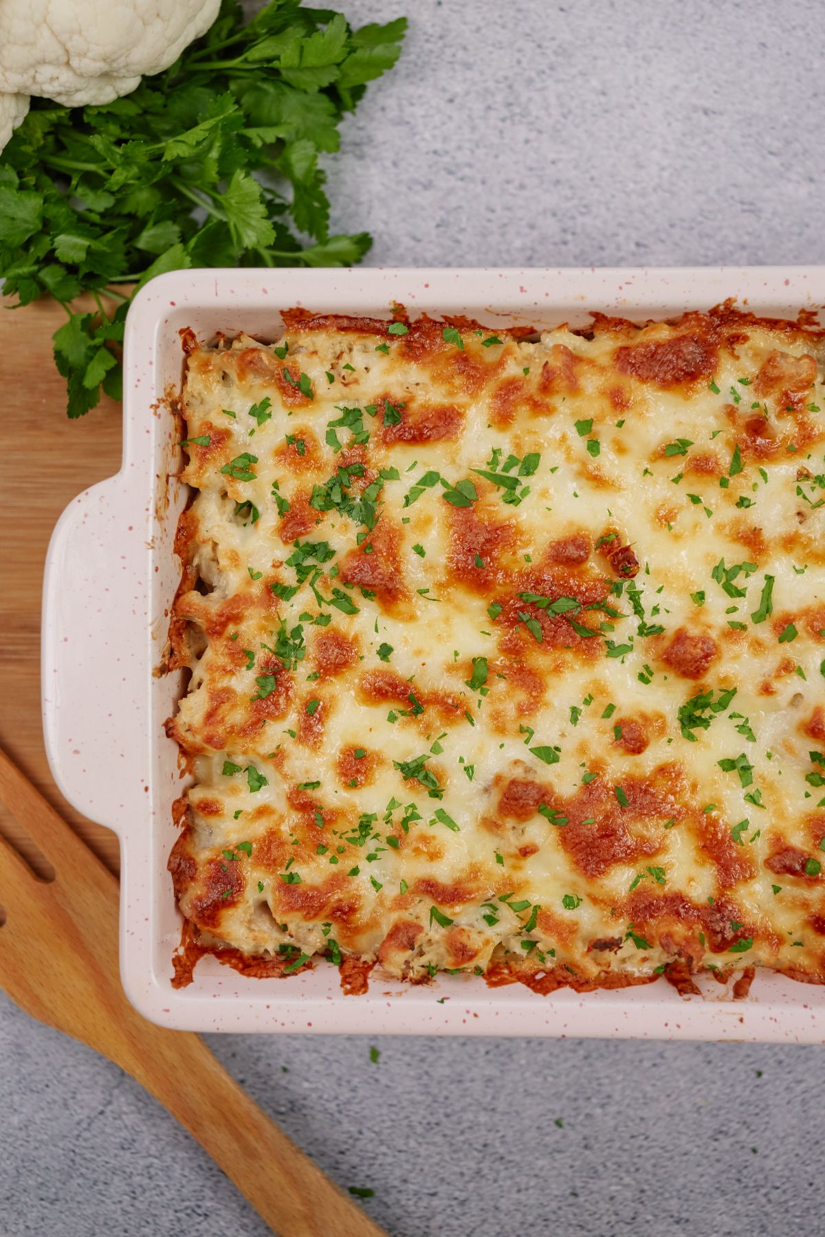 chicken thighs and cauliflower in baking dish covered with cheese