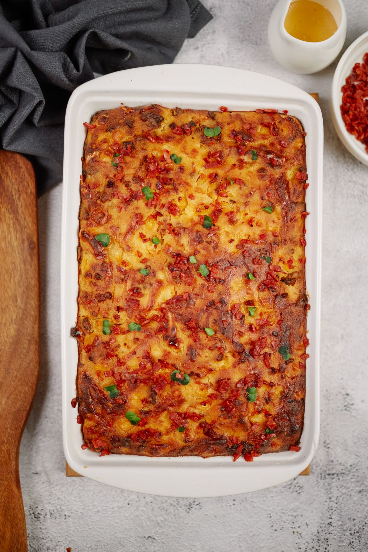 white rectangular baking dish filled with cheesy cornbread with chorizo on marble table