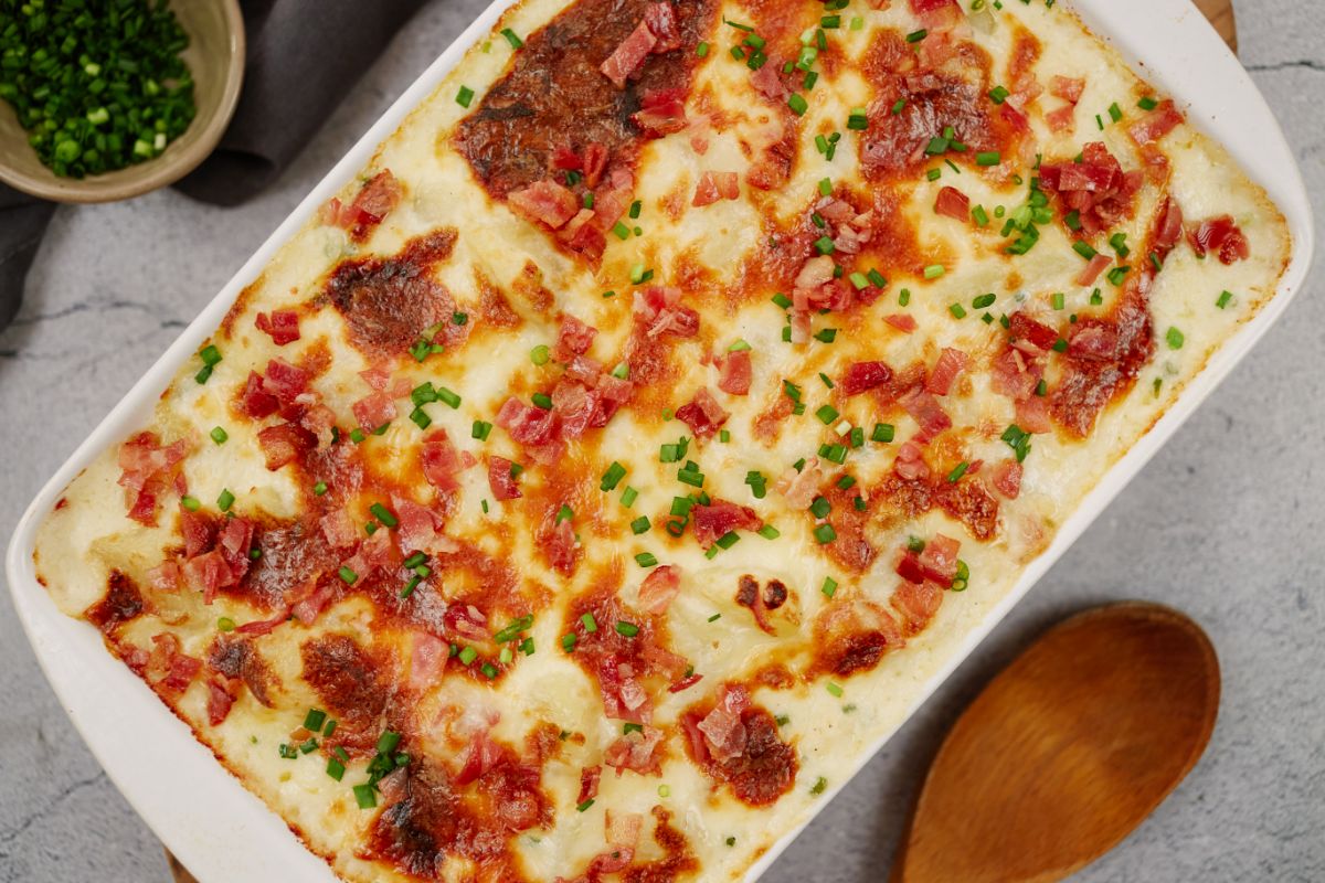 white baking dish filled with potato casserole topped with bacon