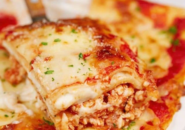 spatula holding a slice of chicken lasagna above baking dish