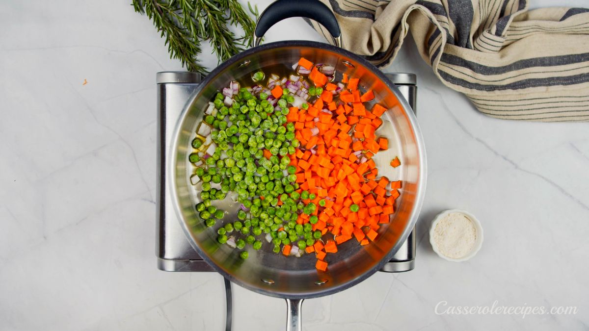 peas carrots and onions in skillet on silver hot plate on marble counter