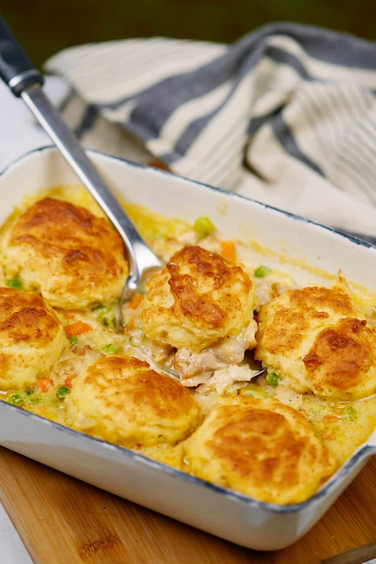 casserole dish of chicken and dumplings on table by striped napkin